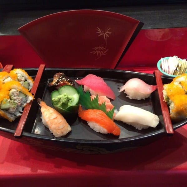 A sushi boat with various nigiri and maki rolls, including tuna, salmon, shrimp, and yellowtail.