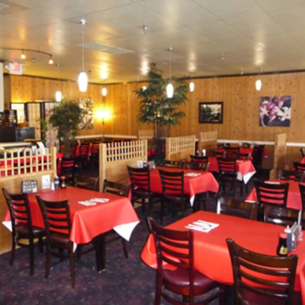Interior of Koibito One Sushi & Teriyaki with red tablecloths, dark chairs, and wood-paneled walls.