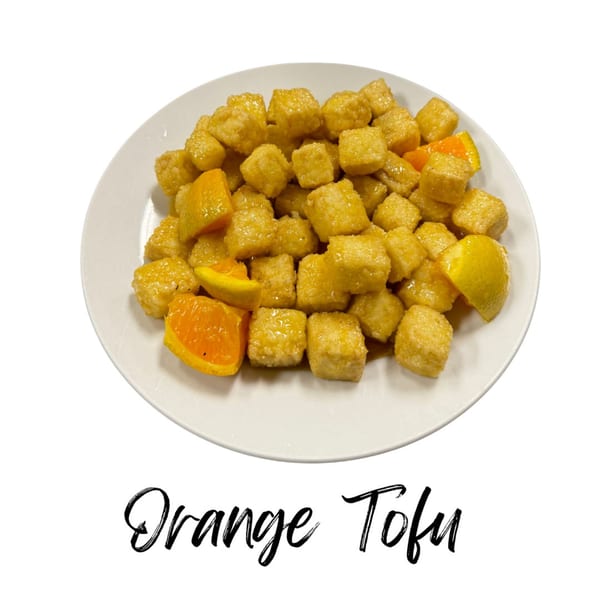 A white plate filled with golden-brown orange tofu cubes and orange slices.