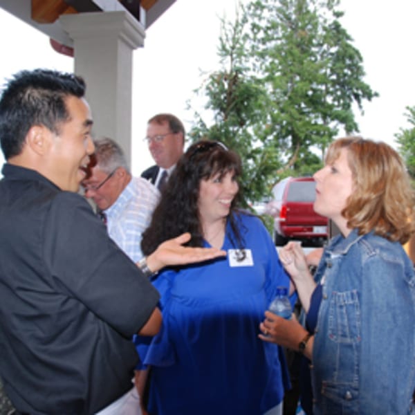 Four people, two men and two women, are engaged in conversation at an outdoor gathering.
