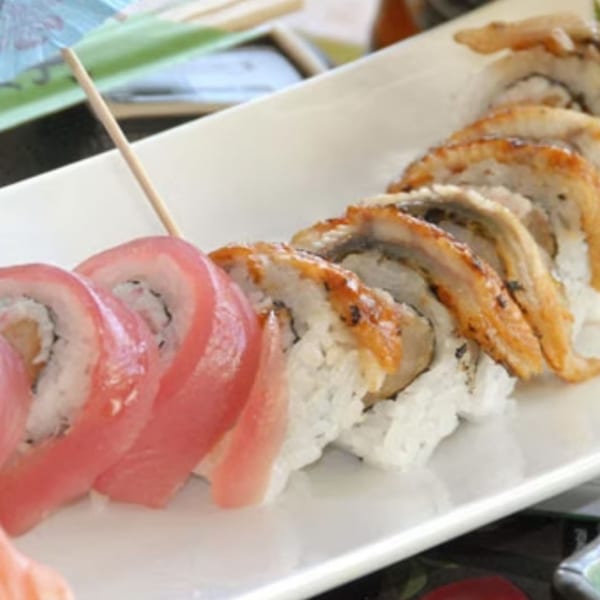 Two types of sushi rolls, one with pink tuna and the other with grilled eel, on a white plate.