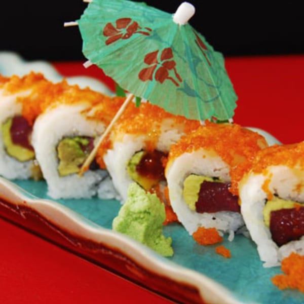 Koibito One Sushi & Teriyaki's sushi rolls with avocado, tuna, and orange roe, garnished with a paper umbrella.