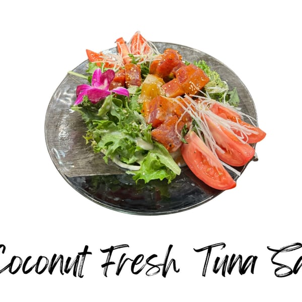 A vibrant Coconut Fresh Tuna Salad with lettuce, tomatoes, and a pink orchid garnish.