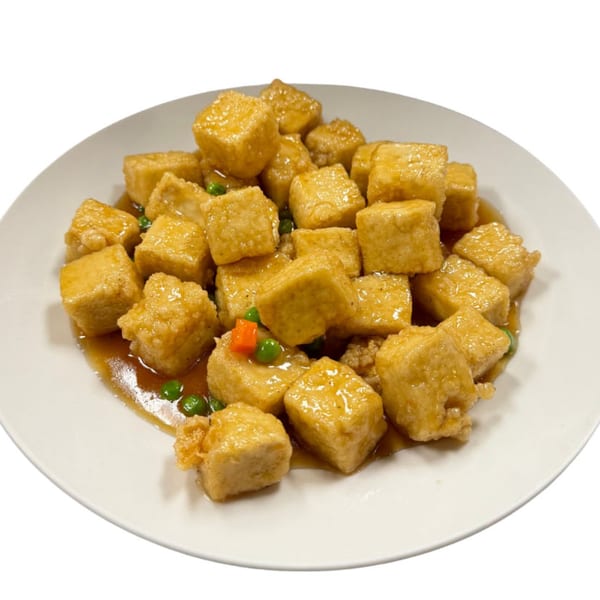 Crispy fried tofu cubes coated in a glossy brown sauce with green peas and diced carrots.