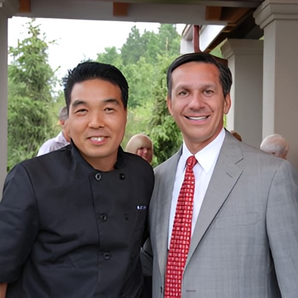 Koibito One Sushi & Teriyaki chef in black uniform posing with a man in a suit.