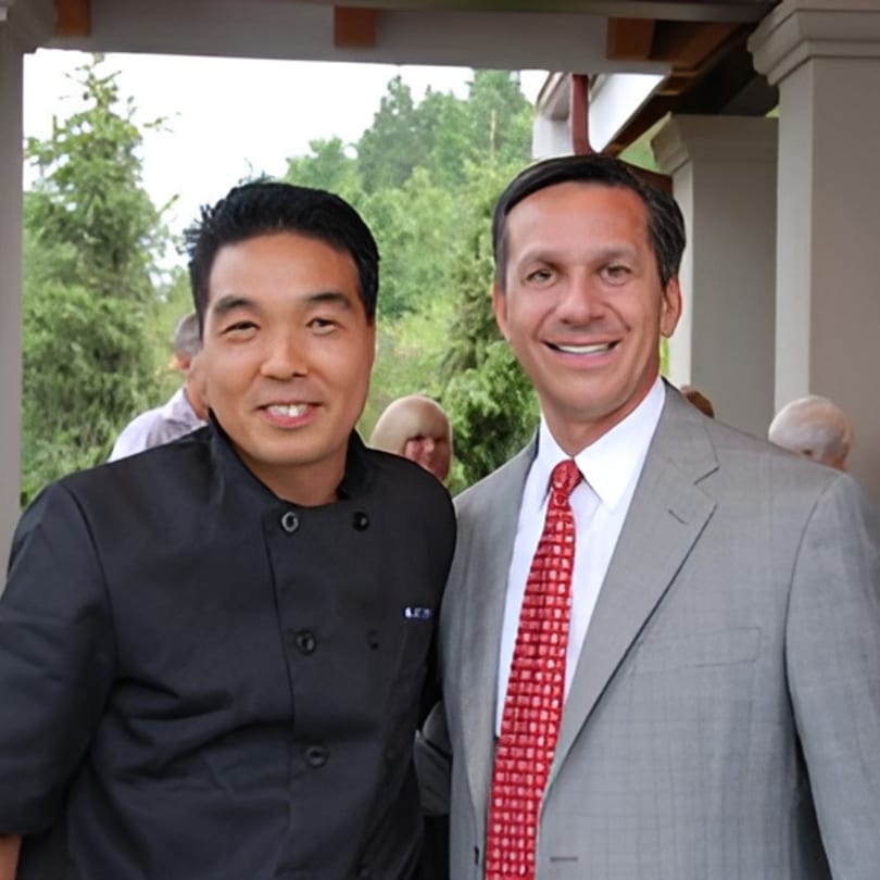 Koibito One Sushi & Teriyaki chef in black uniform posing with a man in a suit.