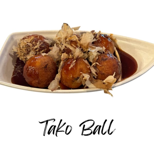 Takoyaki balls with sauce and bonito flakes on a white rectangular plate.