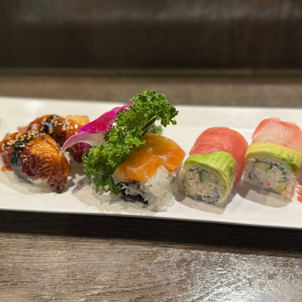 Assortment of Koibito One Sushi & Teriyaki rolls with salmon, tuna, avocado, and eel on a white plate.