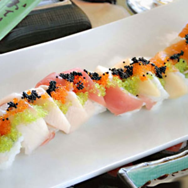A long white plate of Koibito One Sushi & Teriyaki nigiri, topped with colorful roe.