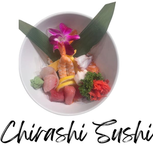 Chirashi sushi bowl with various seafood, lemon, wasabi, ginger, and an orchid garnish.