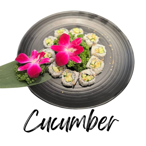 Cucumber sushi rolls with sesame seeds, garnished with pink orchids and green lettuce on a black plate.