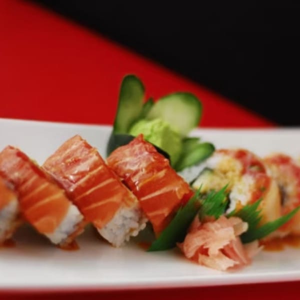 Koibito One Sushi & Teriyaki's salmon sushi rolls with ginger, wasabi, and cucumber on a white plate.