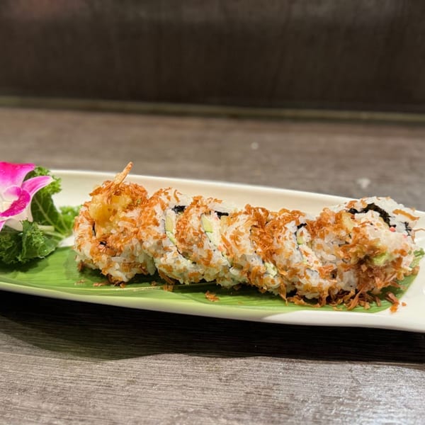 Koibito One Sushi & Teriyaki's crispy sushi roll on a banana leaf with a pink orchid.