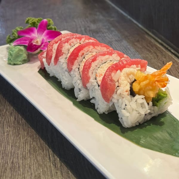 Koibito One Sushi & Teriyaki's sushi roll with red tuna, tempura shrimp, and a pink orchid garnish.