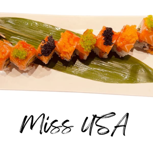 Koibito One Sushi & Teriyaki's salmon sushi rolls topped with black, orange, and green caviar on a leaf.