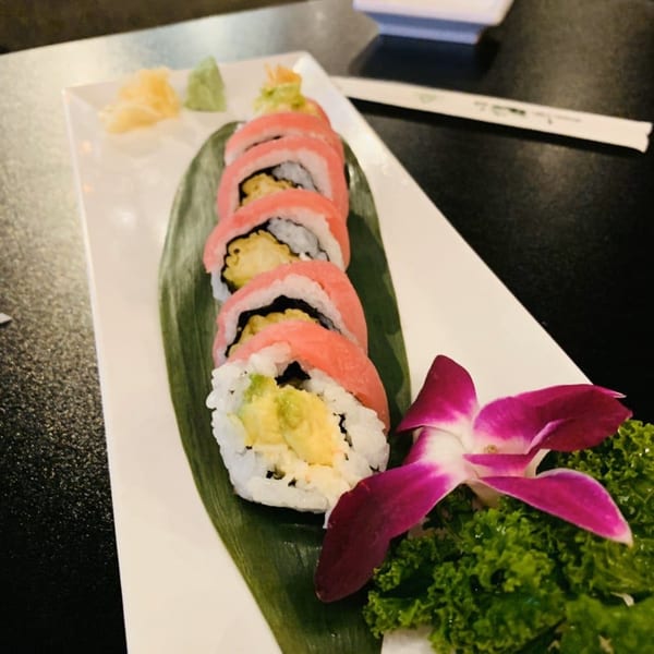 Koibito One Sushi & Teriyaki's tuna sushi roll, garnished with a purple orchid and lettuce.
