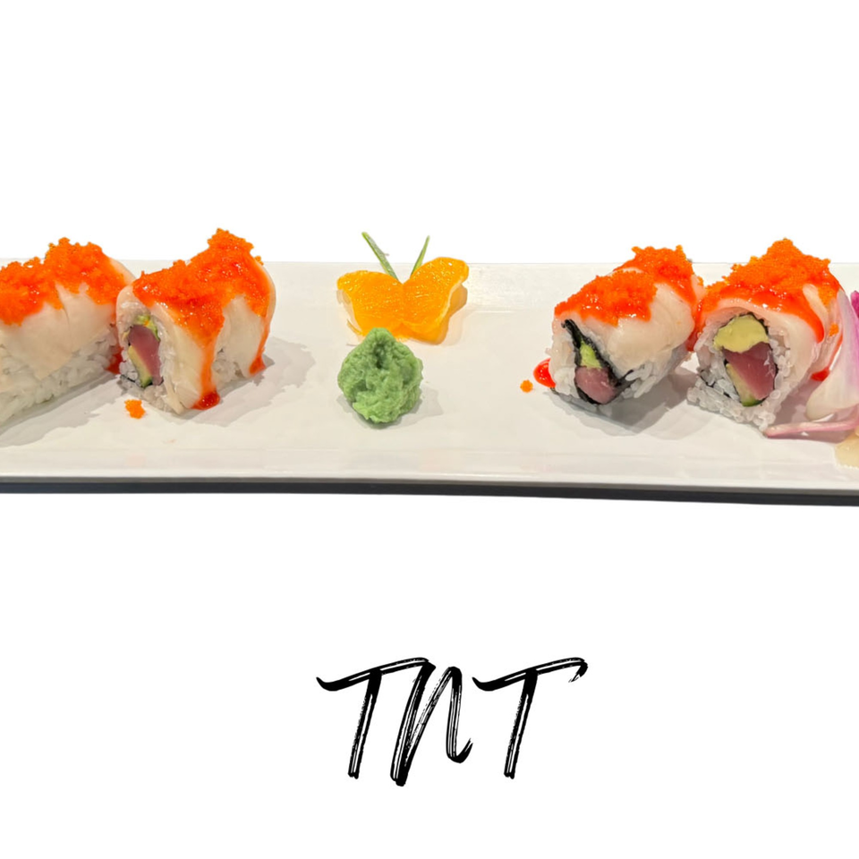 Four pieces of sushi with orange roe, wasabi, and a butterfly-shaped orange slice on a white plate.