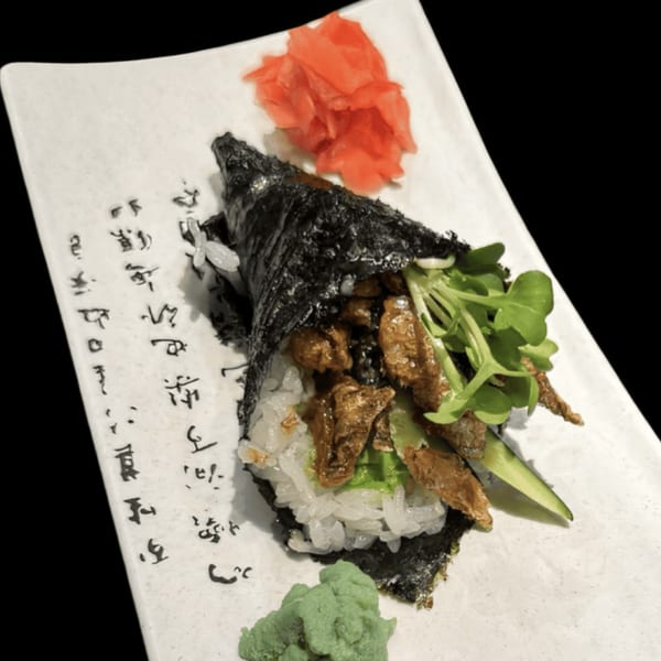 Koibito One Sushi & Teriyaki's hand roll with meat, greens, rice, pickled ginger, and wasabi.