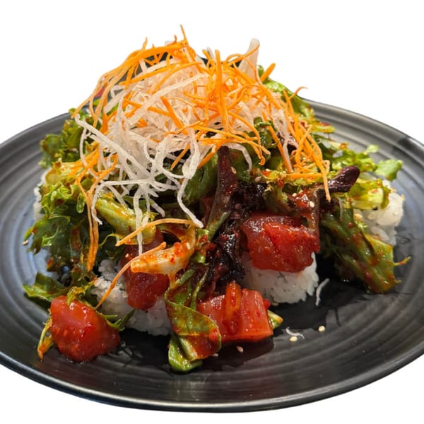 Koibito One Sushi & Teriyaki's spicy tuna salad with shredded carrots and daikon on a black plate.
