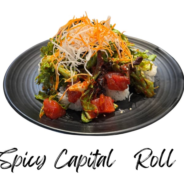 Spicy Capital Roll with tuna, greens, and shredded carrots on a black plate.
