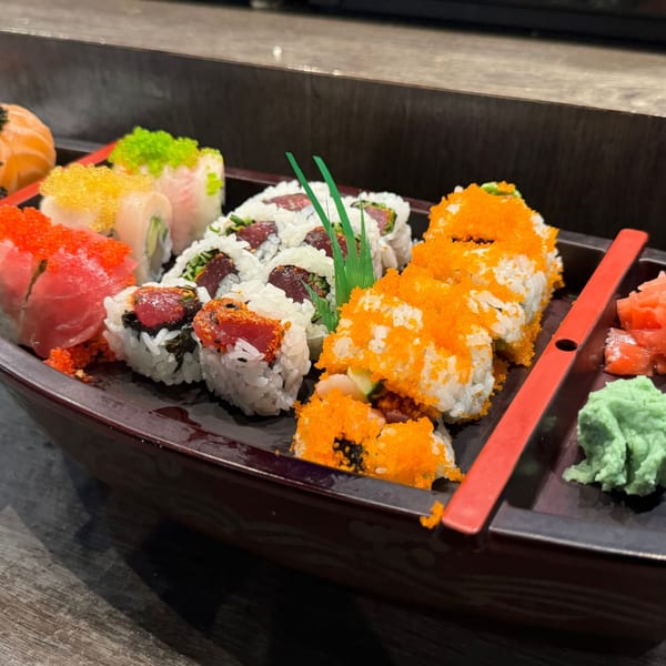 Assorted sushi rolls, including tuna, salmon, and roe-topped varieties, served in a decorative boat.