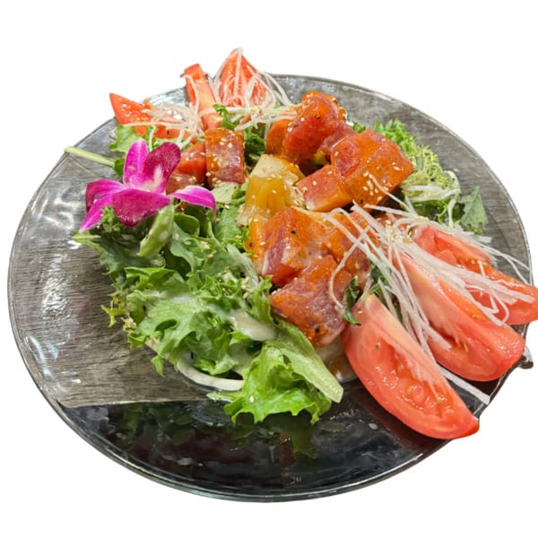 Koibito One Sushi & Teriyaki's poke salad with tuna, lettuce, tomatoes, and a pink orchid.
