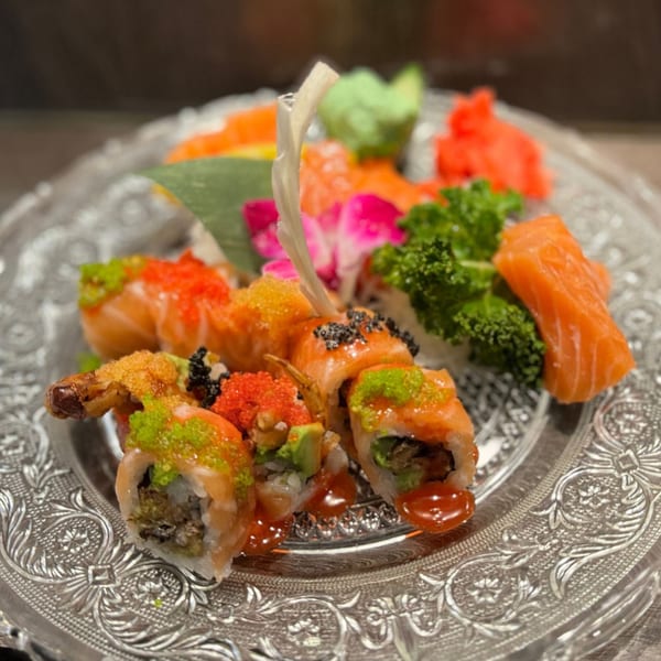 Koibito One Sushi & Teriyaki's sushi platter with various rolls, sashimi, and garnishes on a decorative plate.