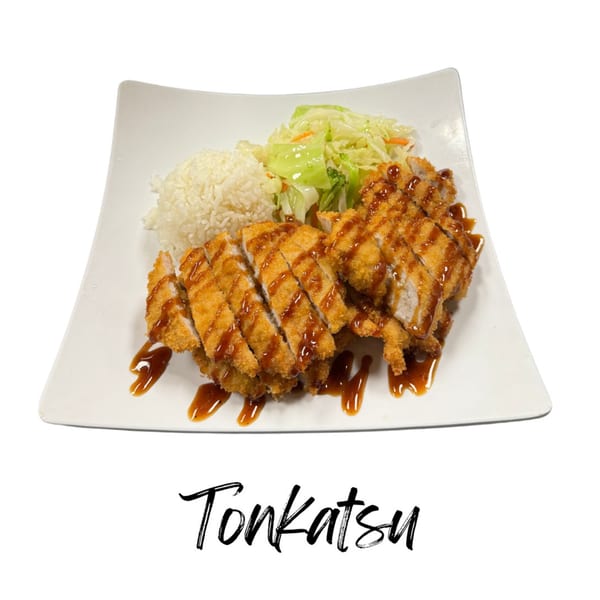 Crispy tonkatsu drizzled with sauce, served with white rice and shredded cabbage on a white plate.