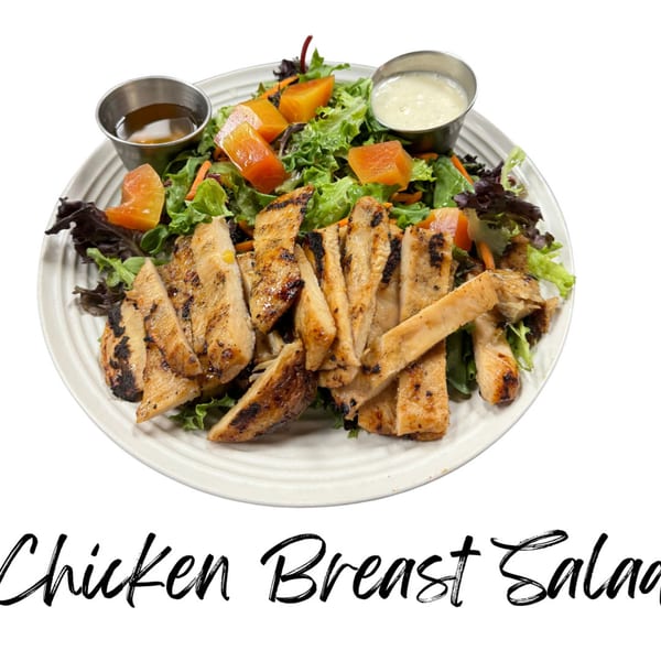 Grilled chicken breast salad with mixed greens, papaya, and two dressing cups on a white plate.