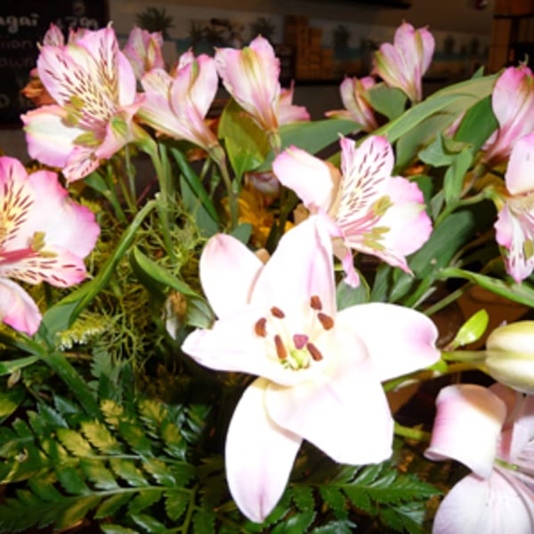 Close-up of a bouquet of pink and white lilies with green foliage, likely a restaurant decoration.