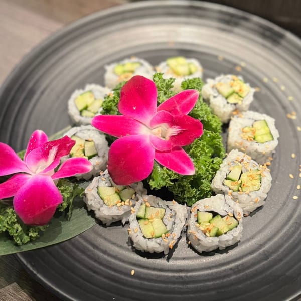 Koibito One Sushi & Teriyaki's cucumber sushi rolls with sesame seeds, garnished with pink orchids and lettuce.