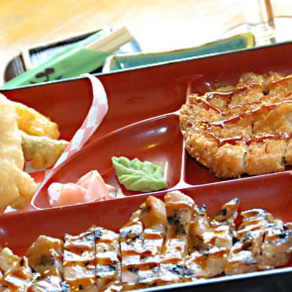 A Koibito One Sushi & Teriyaki bento box with fried tempura, katsu, and sushi rolls.